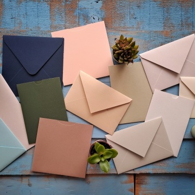 Vários envelopes coloridos e plantas suculentas sobre mesa azul desgastada