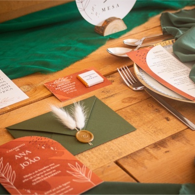 Convites de casamento e decoração de mesa em tons verdes e laranja com selo de cera