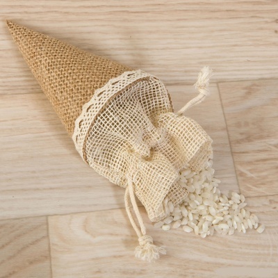 Saco de rede branco dentro de cone de juta castanha com arroz a sair sobre madeira clara