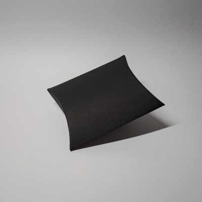 Caixa preta pequena em forma de almofada sobre superfície cinza