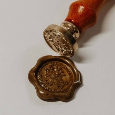 Selo de cera castanho com carimbo de metal e cabo de madeira.