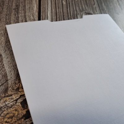 Folha branca texturizada com corte numa mesa de madeira escura