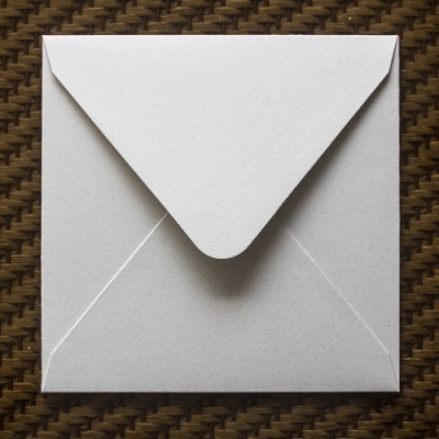 Envelope quadrado branco sobre superfície castanha entrelaçada