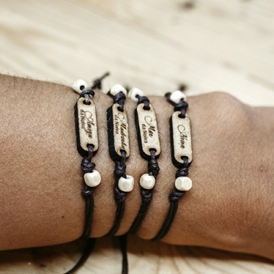 Pulseiras artesanais com placas de madeira gravadas com palavras relacionando mãe, em cordão preto