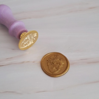 Selo de lacre dourado com cabo roxo em fundo claro