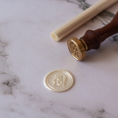 Selo de cera branco com carimbo de metal e cabo de madeira em superfície de mármore