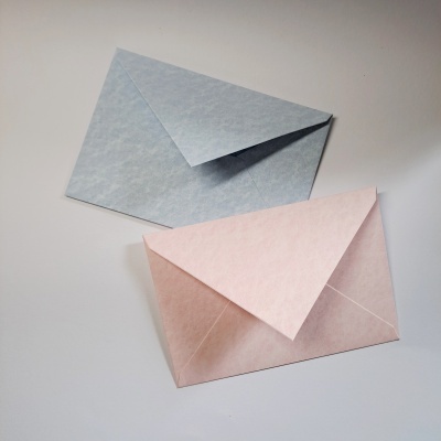 Dois envelopes azul claro e rosa claro sobre superfície branca