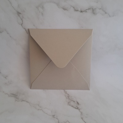 Envelope castanho claro sobre mesa branca com padrão de mármore