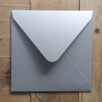 Envelope quadrado cinzento com textura fina sobre madeira natural