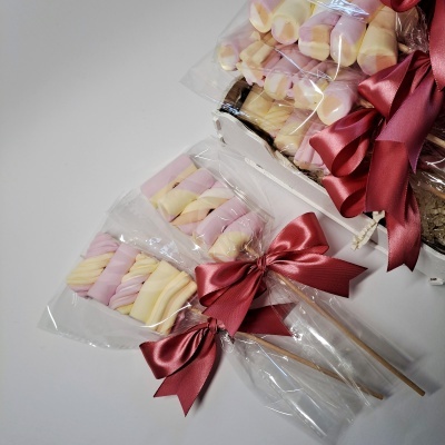 Espectos de marshmallows cor-de-rosa e amarelo com laços vermelhos