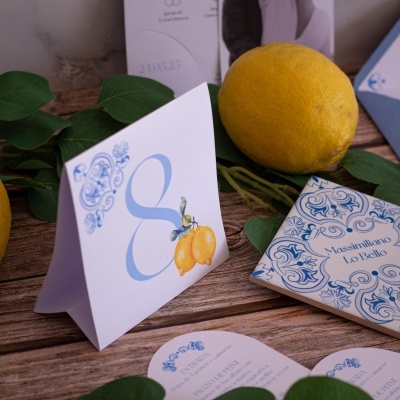 Cartões com estampa de limões e decoração azul sobre mesa de madeira com limões e folhas verdes