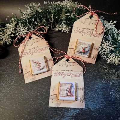 Etiquetas de Natal com notas musicais, texto 'Feliz Natal' e ilustrações de animais em presilhas de madeira