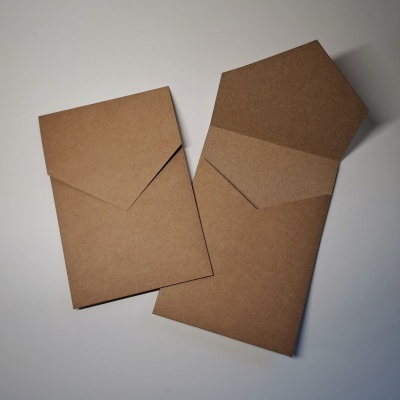 Envelopes de papel kraft castanho, um aberto e outro fechado, sobre superfície branca