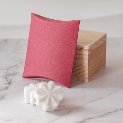 caixa de madeira com embalagem de cartão rosa e peças brancas em forma de flor