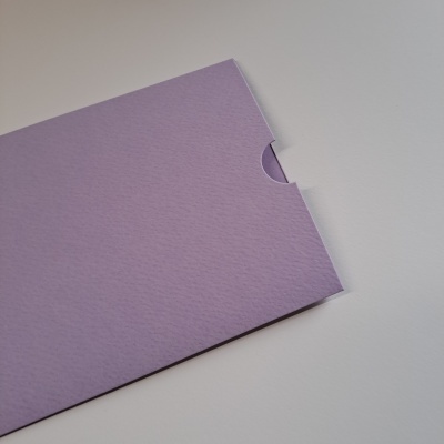 Envelope ou cartão roxo claro com textura numa superfície branca