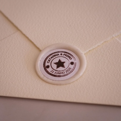 Adesivo redondo branco com estrela preta e texto num envelope creme