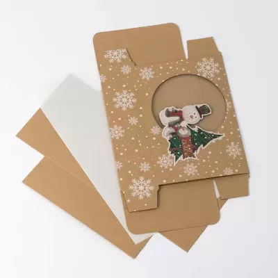 caixa de cartão com padrão de flocos de neve e ilustração de boneco de neve visível por recorte circular