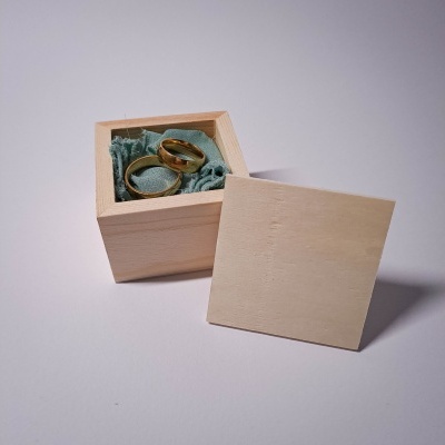 Caixa de madeira com tampo e duas alianças douradas em tecido verde