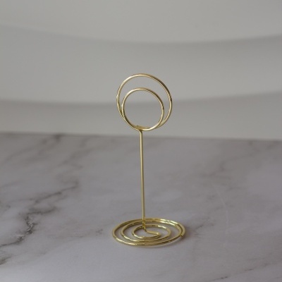 Suporte metálico dourado para fotos ou notas em superfície de mármore