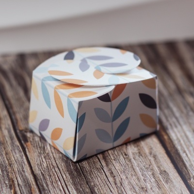 Caixa pequena com padrão de folhas coloridas sobre superfície de madeira