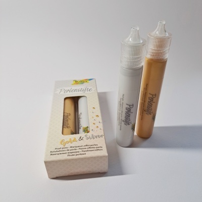 Dois tubos de brilho branco e dourado com embalagem branca etiquetada 'Perlensifte Gold & Silver'.