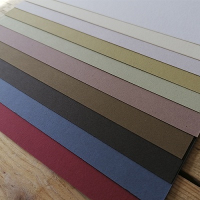 Folhas de papel colorido alinhadas com texturas lisas sobre madeira