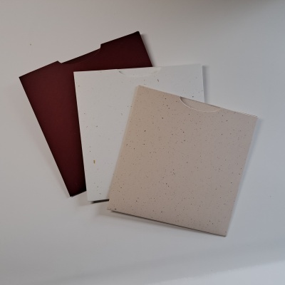 Três envelopes de papel reciclado em tons castanho, creme e bege