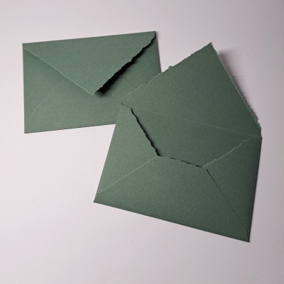 Dois envelopes verdes de papel com bordas recortadas, um aberto e um fechado sobre fundo branco.