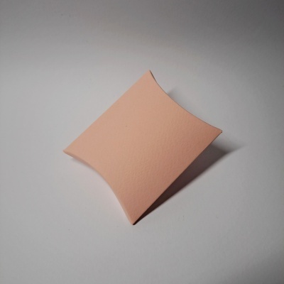 Caixa pequena em forma de almofada cor salmão sobre fundo branco