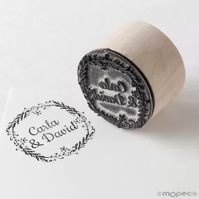 Carimbo redondo de madeira com relevo floral carimbado em papel branco com texto Carla & David