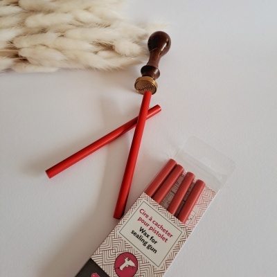 Varetas vermelhas para pistola de lacre e ferramenta de lacre em madeira sobre fundo branco