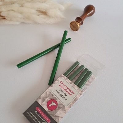 Varetas verdes para lacre de cera em embalagem com selo de madeira e plantas secas ao fundo