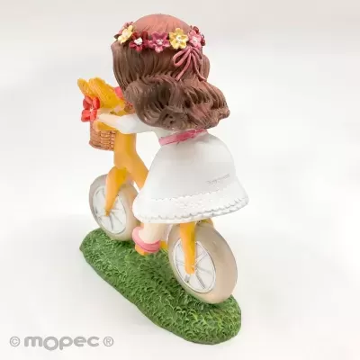 Figurina de menina de vestido branco com bicicleta amarela sobre base verde