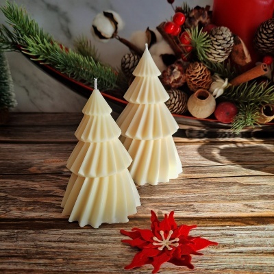 Duas velas brancas em forma de árvore de Natal num ambiente decorado com pinhas e plantas naturais