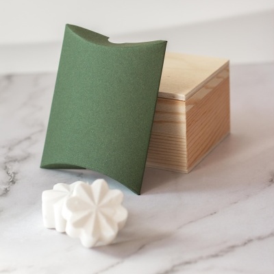 Caixa de madeira com embalagem verde e sabonetes brancos florais