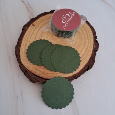 Etiqueta de papel verde escuro com borda ondulada sobre tronco de madeira