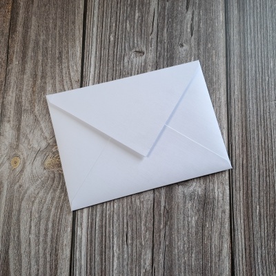 Envelope branco fechado sobre superfície de madeira envelhecida