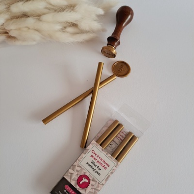 Varetas douradas para lacre com selo de lacre e embalagem, sobre fundo branco com palha decorativa