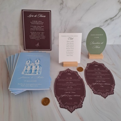 Conjunto de convites e elementos gráficos para casamento de Jéssica e André em várias cores sobre mesa de mármore