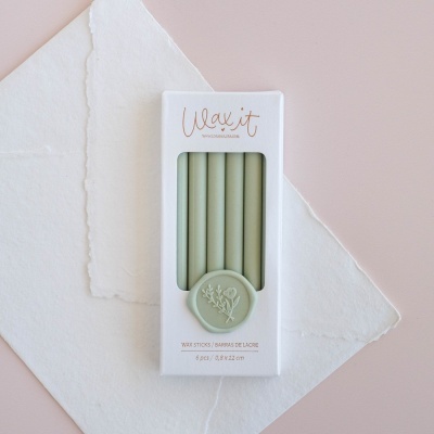 Cinco velas verdes em caixa branca com janela e texto visível Wax it e informações do produto