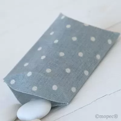 Saco de tecido azul com bolinhas brancas contendo objeto branco oval