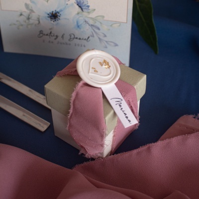 Caixa de presente decorada com fita rosa e selo branco com detalhes dourados
