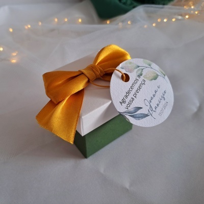 Caixa de presente com fita amarela e etiqueta redonda com texto em português
