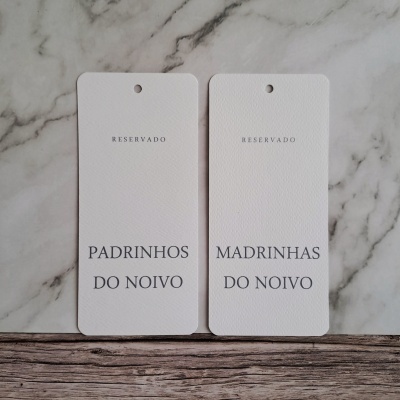 Marcadores de papel brancos com texto RESERVADO PADRINHOS DO NOIVO e RESERVADO MADRINHAS DO NOIVO