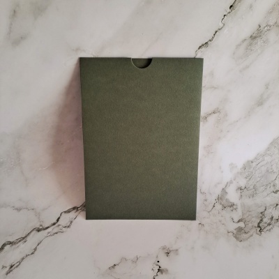 Almofada de papelão verde escuro sobre superfície de mármore branca