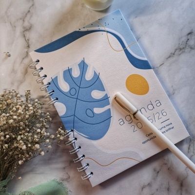 Agenda 2025/26 com capa colorida e caneta branca sobre mesa de mármore