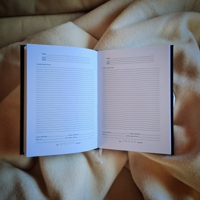 Caderno aberto com páginas para escrita sobre tecido branco macio