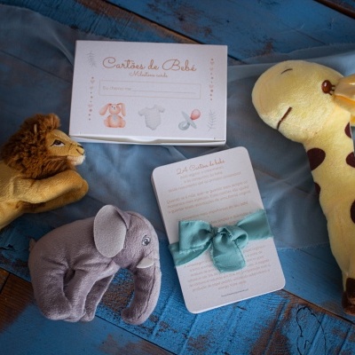 Fantoches de peluche e cartão 'Cartões de Bebé' sobre superfície de madeira azul