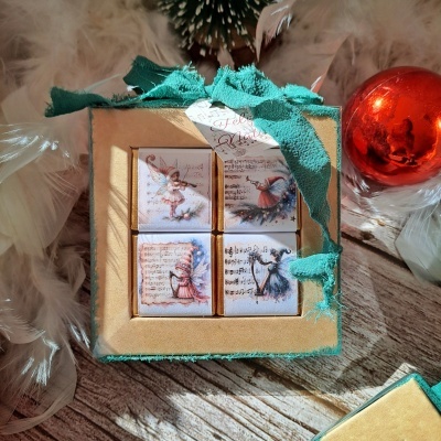 Conjunto de chocolates quadrados com ilustrações de anjos em caixa decorada com fita verde
