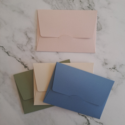 Conjunto de envelopes coloridos em papel texturizado sobre mármore branco